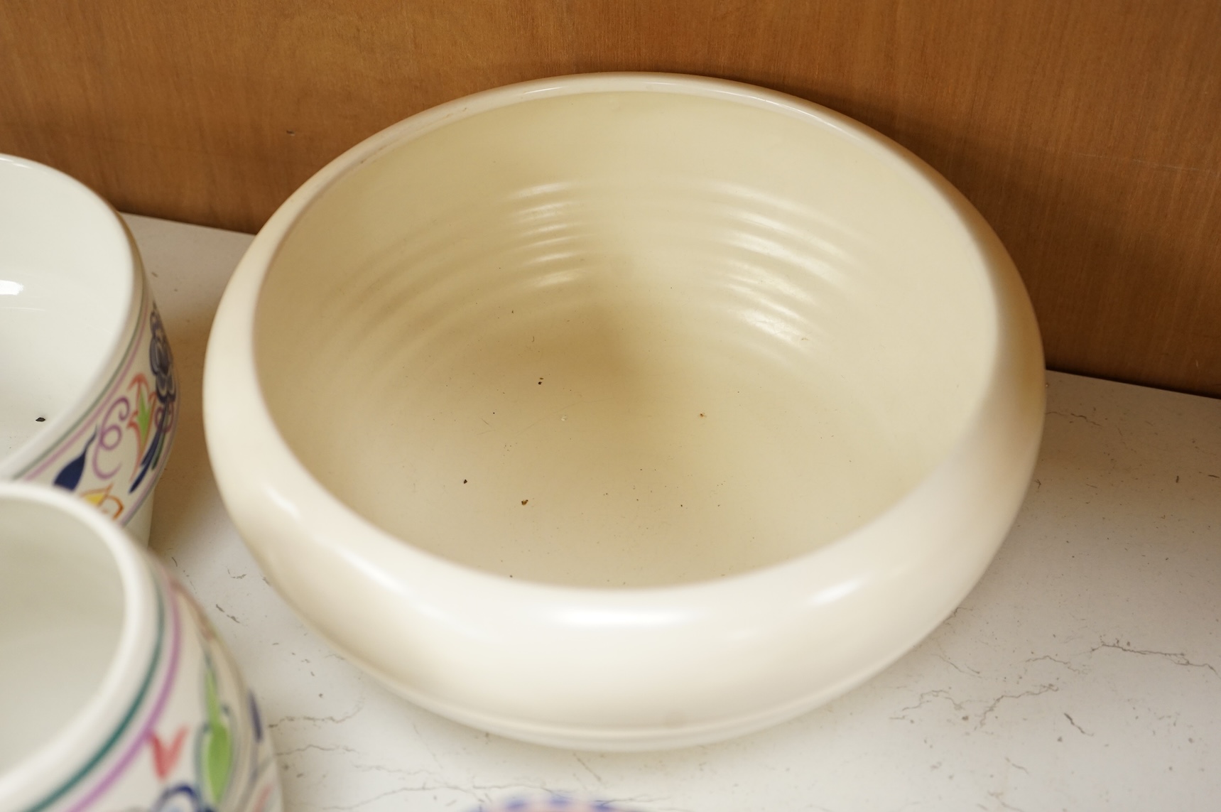 A collection of eight Poole pottery pieces to include vases, bowls and a jar and cover, largest 28cm in diameter